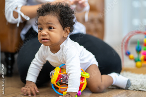 A baby is crawling on the floor and playing with a toy