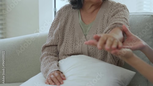 Caregiver elderly care at home with hand support, compassion, nursing guidance, patient comfort on sofa gentle touch, physical therapy hand exercise, living room help, trust, dignity