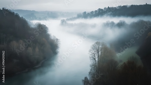 Misty river valley emerging through ethereal fog, creating a dreamlike landscape vista.