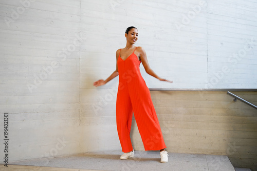Poised woman dressed colorfully strikes confident pose next to city building with soft natural light