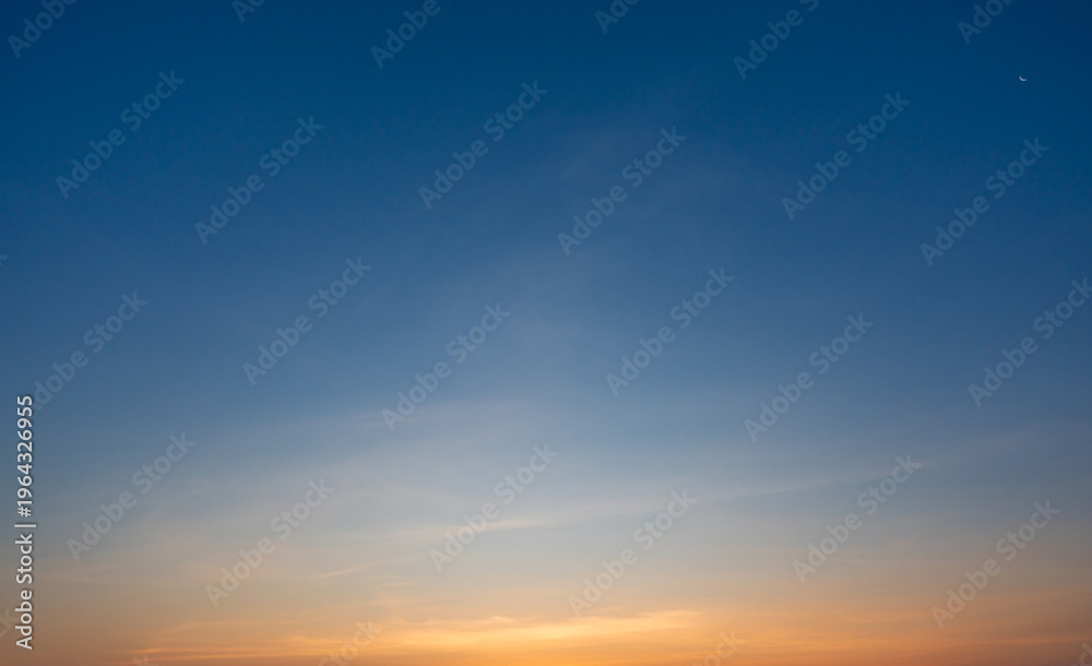 Fototapeta premium Clear blue sky at sunrise with subtle clouds and warm light forming a peaceful mood.