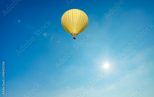 Gelber Heissluftballon vor einem blauen Himmel