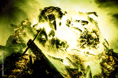 Bonfire flames and smoke creating an intense glow from burning wood