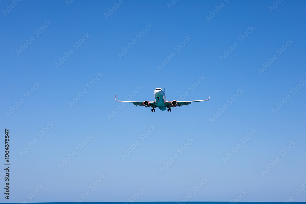 Fototapeta premium Aircraft landing at Phuket International Airport over Mai Khao Beach, Thailand.