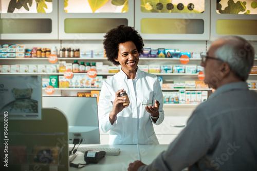Smiling pharmacist advising senior customer at pharmacy counter