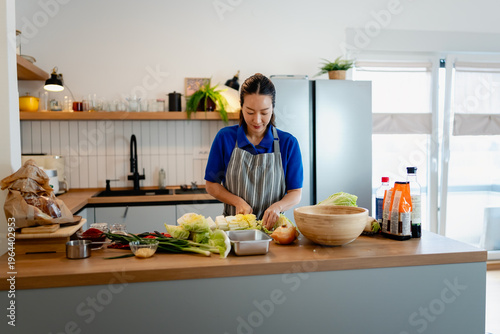 Foto East Asian woman preparing kimchi in a modern kitchen, mixing napa cabbage with spices