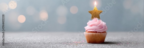 Pink cupcake with star candle on glittery surface for celebrations
