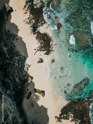 Aerial view of secluded tropical beach with turquoise water and rocky shore