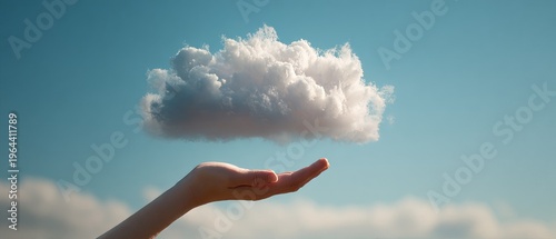 Hand holding fluffy cloud against clear blue sky background