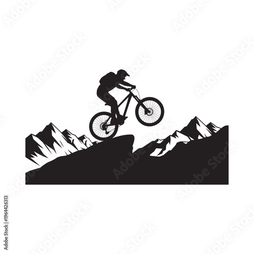 Silhouette of a mountain biker performing a wheelie against a mountain backdrop