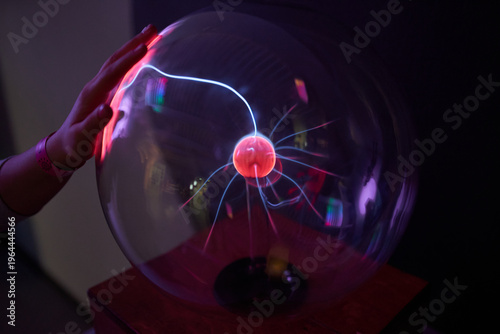 A person touching a plasma ball in a dark room.