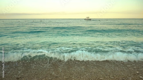 Early morning on a tropical beach. The rays of the rising sun illuminate the sandy seashore. Small waves roll onto the sand. An idyllic picture of a tropical resort in the early morning.4k slow motion