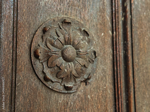 Carved decoration, flower-shaped ornament on an old wooden door.