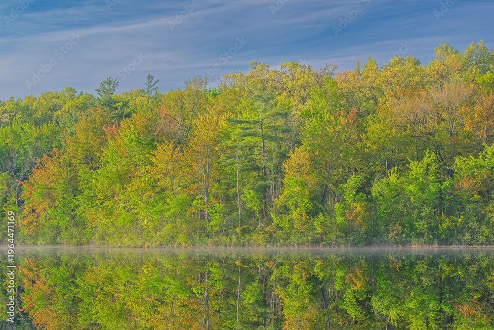 Fototapeta premium Spring landscape at sunrise of the shoreline of Long Lake with mirrored reflections in calm water, Yankee Springs State Park, Michigan, USA