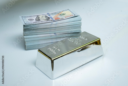 Fine silver bar and pile money banknote 100 USD on a gray background