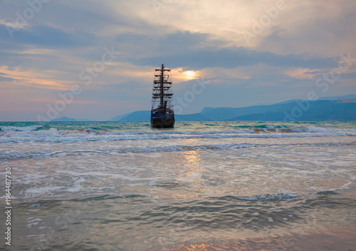 Sailing old ship in storm sea heavy sunset clouds in the background