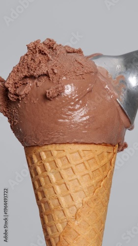 4k vertical video Chocolate ice cream scoop in waffle cone with spoon taking bite Close-up creamy texture and rich brown tone, ideal for dessert food concept product advertising and summer refreshment