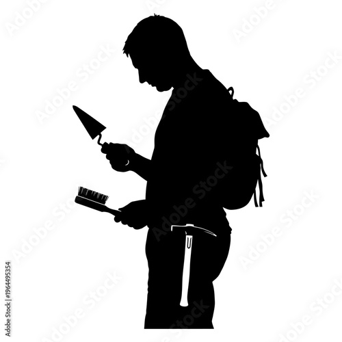 Silhouette of an archaeologist examining tools for excavation and research.