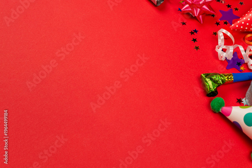Festive golden and purple stars of confetti  and a present, birthday caps on a red background.