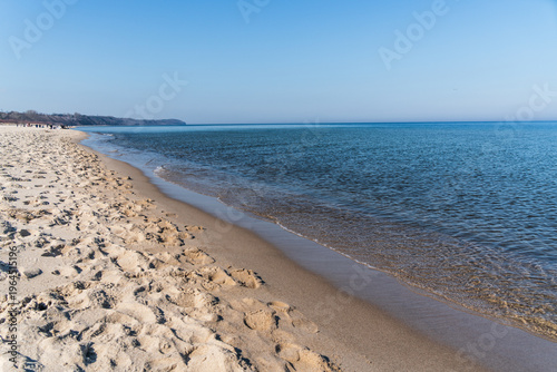 Sandy beach and calm Baltic Sea waters under a clear blue sky in Wladyslawowo