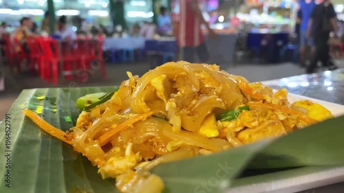 Thai Pad Thai noodle dish close-up at a street food stall, authentic Thai cuisine with egg and bean sprouts.