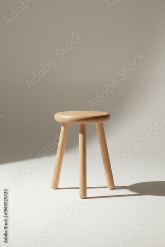 Wooden stool on a plain background with natural light casting shadows