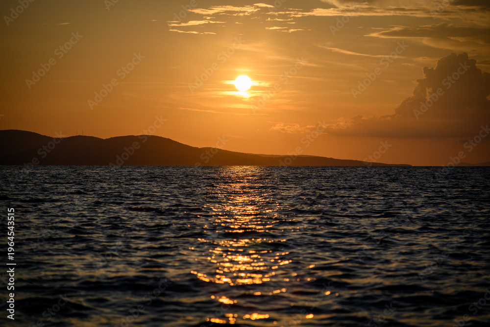 Obraz premium Golden sunset over ocean with island silhouettes