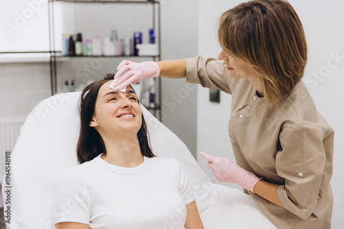 Woman getting her skin cleansed and cared for by a professional aesthetician in a wellness spa setting