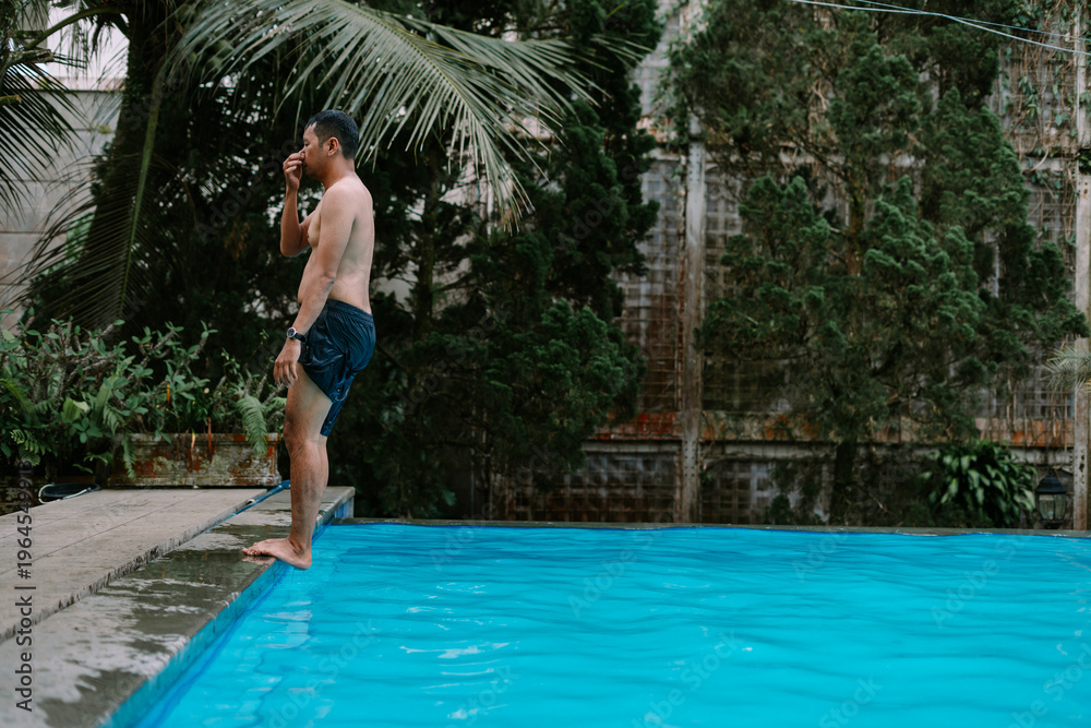 Naklejka premium Man diving into pool surrounded by greenery