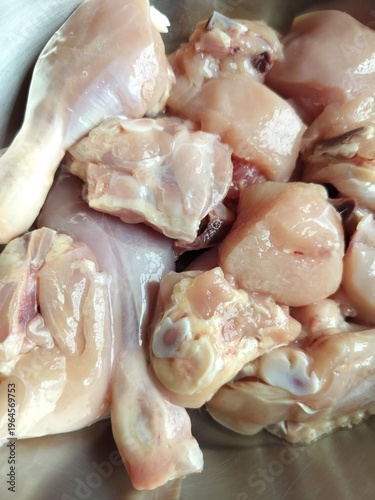 Raw chopped broiler chicken pieces, fresh uncooked cleaned common popular meat chicken cut display in close view.