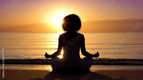 A serene female silhouette practicing yoga meditation on a beach at sunset. Perfect for wellness, mindfulness, and relaxation content.