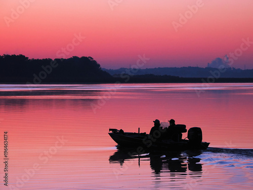 Two Silhouetted Fishermen Heading Out Before Sunrise in Their Bass Boat for a Day Of Fishing