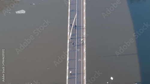 Pedestrian bridge above water, people walking on river crossing, aerial view