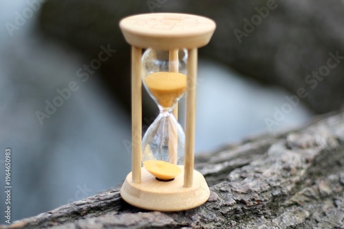 Hourglass as a symbol of passing time outdoor park nature tree background	
