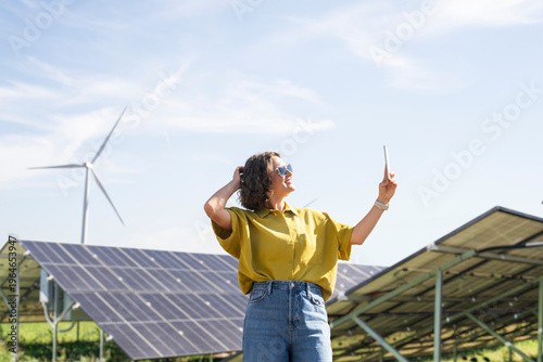 Wallpaper Mural Woman with smartphone at clean energy site solar and wind power farm Torontodigital.ca