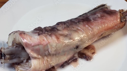 Piece of boiled kingklip on plate, top view close-up