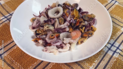 Mix of boiled seafoods in white bowl on checkered napkin