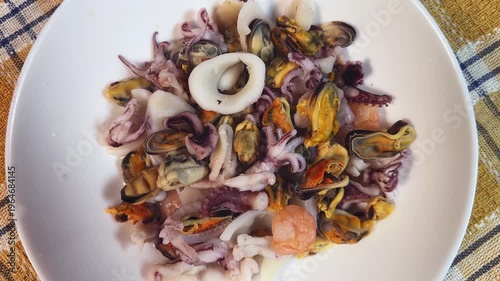Mix of boiled seafoods in white bowl on checkered napkin