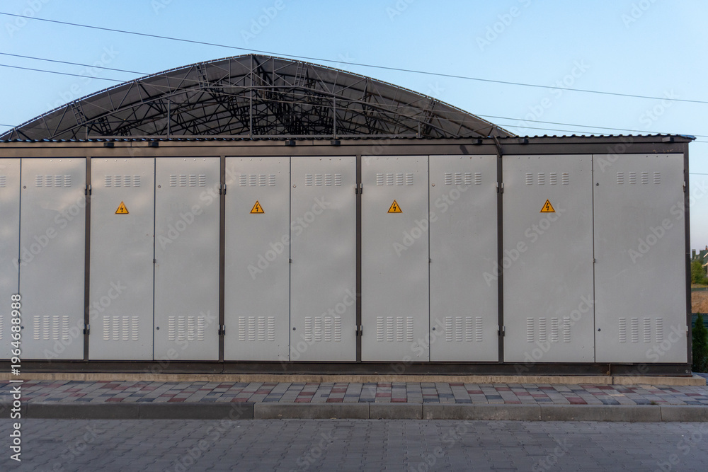 Fototapeta premium Utility Boxes Located Near a Large Metal Structure in an Urban Area During Late Afternoon With Clear Skies