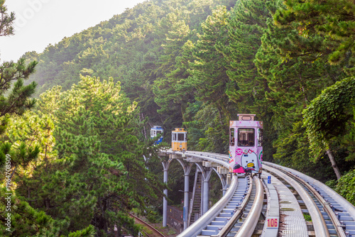Canvas Print Colorful oceanfront capsule cars travel along an elevated coastal rail, offering scenic seaside views and a relaxed tourism experience over the water