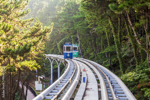 Photography Colorful oceanfront capsule cars travel along an elevated coastal rail, offering scenic seaside views and a relaxed tourism experience over the water