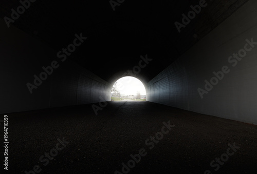Darken concrete tunnel with bright light at the end
