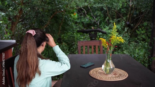 Woman birdwatching with binoculars in lush green forest