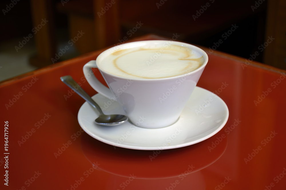 Obraz premium A cup of coffee with foam on a red table