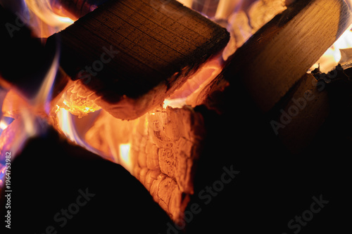 Close up of burning wood logs in a fireplace with bright orange flames. Cozy home atmosphere and heat concept. Warm winter fireplace background or campfire texture, selective focus