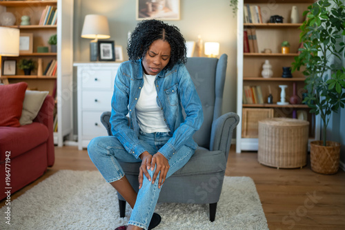 Young black woman experiencing knee pain at home