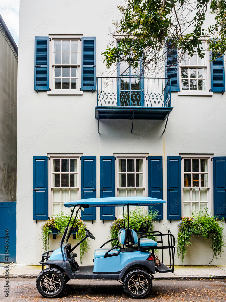 Obraz premium Golf cart parked in front of historic house with blue shutters and balcony in Charleston, SC