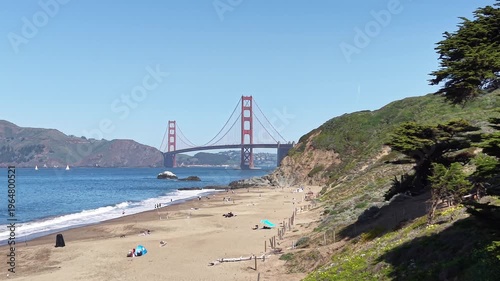 A Medium shot dolly-in aerial drone video capturing the Golden Gate Bridge from the vantage point of Baker Beach.