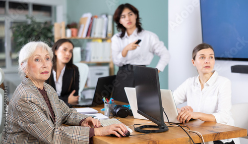 Photos Focused female colleagues watching a project demonstration and working on comput