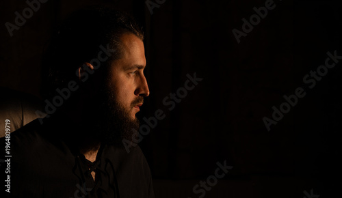 beard man profile face portrait dark hair dramatic mysterious atmosphere black background empty copy space